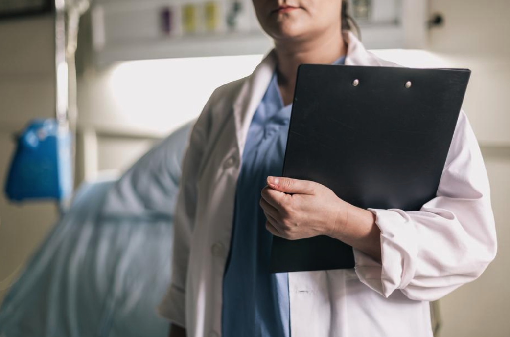 Can I sue my doctor for negligence? Doctor standing near hospital bed with clip board.